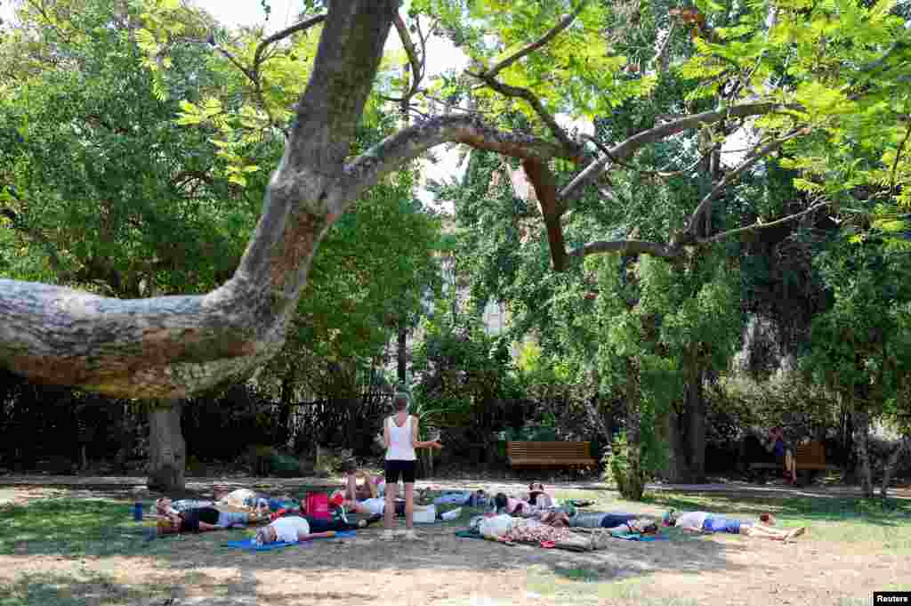 Un grupo de personas aprovecha las sombras de los árboles para practicar yoga en Niza Francia, el 18 de julio de 2022.