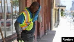 Anthony Harris wipes sweat from his face as he works with E-Z Bel Construction along Fredericksburg Road during an excessive heat warning in San Antonio, Texas, July 19, 2022. 