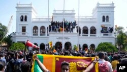 Waandamanaji, baadhi yao wakiwa wamebeba bendera ya taifa, wakiwa katika ofisi za waziri mkuu Ranil Wickremesinghe. wanamtaka Ranil, ambaye sasa ni kaimu rais, waondoke madarakani. PICHA: AP
