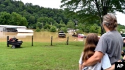 Bonnie Combs hugs her 10-year-old granddaughter Adelynn Bowling as her property becomes covered by the North Fork of the Kentucky River in Jackson, Ky., July 28, 2022. 
