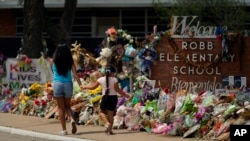 Visitors walk past a makeshift memorial honoring those recently killed at Robb Elementary School, July 12, 2022, in Uvalde, Texas. 