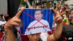 FILE: A Myanmar nationals living in Thailand holds a picture of Senior Gen. Min Aung Hlaing, head of the military council as they protest outside Myanmar's embassy in Bangkok, Thailand, July 26, 2022. 