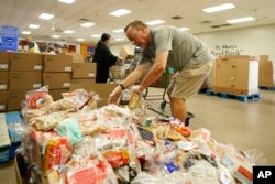 Volunteers fill up grocery carts with food for distribution into drive through vehicles at the St. Mary's Food Bank Wednesday, June 29, 2022, in Phoenix.