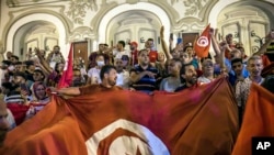 FILE: Tunisians celebrate the exit polls indicating a vote in favor of the new Constitution, in Tunis, July 25, 2022.