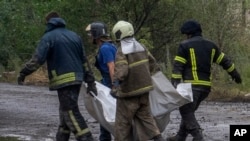 Ukrainian emergency workers carry the lifeless body of a victim found under rubble after a Russian rocket attack hit an apartment buildings late Saturday, in Chasiv Yar, Donetsk region, eastern Ukraine, July 11, 2022.