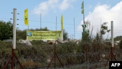 FILE - A pro-Hezbollah placard reads "Our votes and our rockets are accurate" on the Lebanese side of the border with Israel, July 3, 2022.