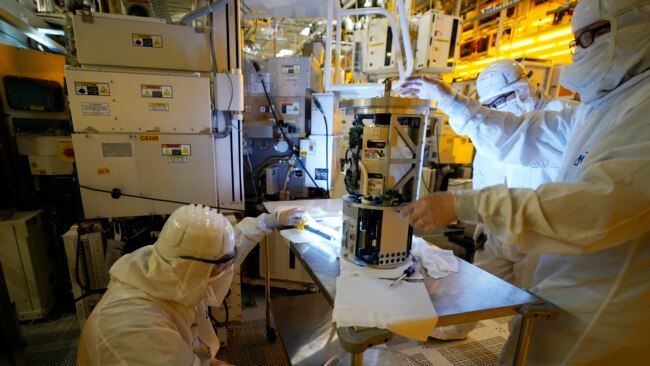 FILE - Technicians inspect a piece of equipment during a tour of the Micron Technology automotive chip manufacturing plant in Manassas, Virginia, Feb. 11, 2022.