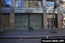 FILE - A woman passes a shop that closed after the economy crisis in the commercial area in Beirut, Lebanon on January 12, 2022. (AP Photo/Hussein Malla, File)