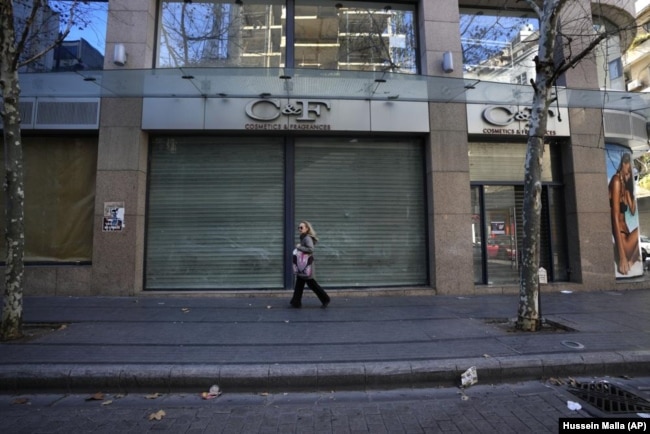 FILE - A woman passes a shop that closed after the economy crisis in the commercial area in Beirut, Lebanon on January 12, 2022. (AP Photo/Hussein Malla, File)