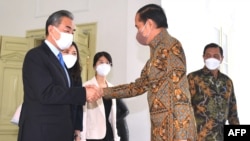 This handout taken, released by the Presidential Palace, July 11, 2022 shows Indonesia's President Joko Widodo (R) shaking hands with China's Foreign Minister Wang Yi (L) at the Merdeka Palace in Jakarta. (Photo by Rusman / Indonesia's Presidential Palace/AFP)