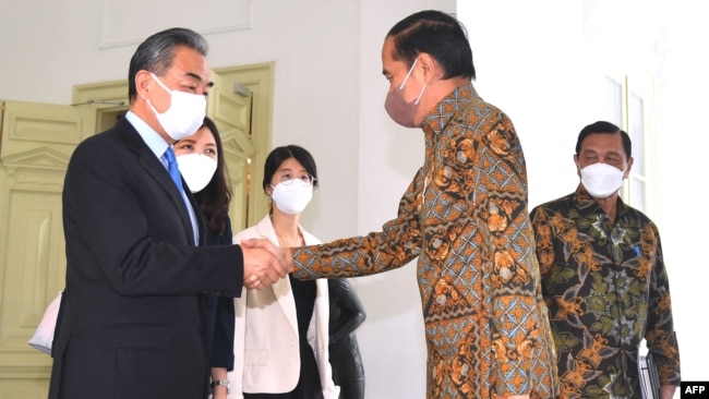 This handout taken, released by the Presidential Palace, July 11, 2022 shows Indonesia's President Joko Widodo (R) shaking hands with China's Foreign Minister Wang Yi (L) at the Merdeka Palace in Jakarta. (Photo by Rusman / Indonesia's Presidential Palace/AFP)