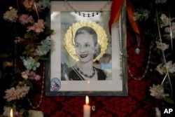Sebuah lilin, di sebelah gambar mendiang mantan ibu negara Argentina María Eva Duarte de Perón, lebih dikenal sebagai "Evita", di restoran "El Santa Evita", di Buenos Aires, Argentina, pada 24 Juli 2022. (AP Photo/Natacha Pisarenko)