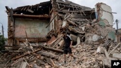 Čoveke pretražuje ostatke uništene kuće u oblasti Harkov, 16. jula 2022. (Foto: AP/Evgeniy Maloletka)