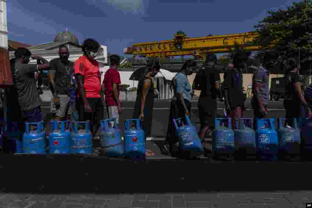 People wait in a queue with empty cylinders to buy domestic gas at a distribution center, in Colombo, Sri Lanka, July 12, 2022.