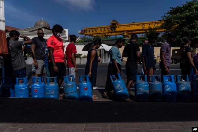 People wait in a queue with empty cylinders to buy domestic gas at a distribution center, in Colombo, Sri Lanka, July 12, 2022. (AP Photo/Rafiq Maqbool)