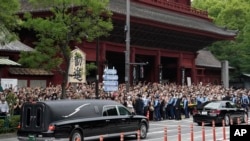 日本前首相安倍晋三的葬礼举行后，运载安倍棺木的灵车离开寺庙，日本民众路旁送行。（2022年7月12日）