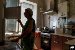 Lyubov Mahlii, 76, checks her freezer while cooking in her apartment in Sloviansk, Donetsk region, eastern Ukraine, Aug. 7, 2022.