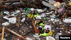 Members of the Tennessee Task Force One search and rescue team wade through debris-filled Troublesome Creek in Perry County, Kentucky, after a search dog detected the scent of a potential victim on July 31, 2022. (Jeff Faughender/USA Today Network via Reuters)