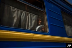 FILE - An internally displaced girl looks out the window of a train heading to Dnipro, in the Pokrovsk train station, Donetsk region, eastern Ukraine, July 6, 2022. Tens of thousands of evacuees have already returned to communities close to the Donetsk region's front line.