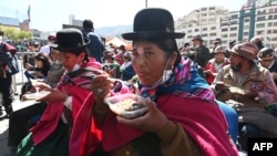 Una mujer indígena aymara tiene una porción del plato más grande de Bolivia, el chairo, una sopa tradicional del pueblo aymara a base principalmente de verduras y carne seca de cordero, plaza San Francisco de La Paz el 1 de julio de 2022.