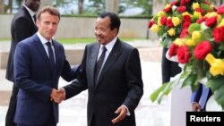 Cameroon's President Paul Biya shakes hands with his French counterpart Emmanuel Macron at the presidencial palace in Yaounde, Cameroon, July 26, 2022. 