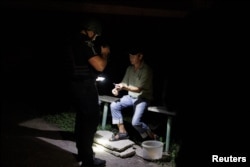 A police officer checks the documents of a civilian during a night patrol after curfew, as Russia's attack on Ukraine continues, in Kramatorsk, Ukraine, Aug. 5, 2022.
