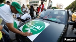 A man distributes stickers urging Tunisians to vote "yes" in a referendum for a new constitution, in Habib Bourguiba Avenue in downtown Tunis, Tunisia, July 23, 2022. 