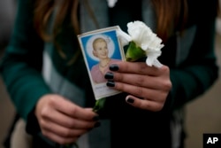 Seorang perempuan memegang foto mendiang ibu negara Argentina Maria Eva Duarte de Peron, lebih dikenal sebagai Evita, saat dia menunggu gilirannya untuk mengunjungi makam Evita di Buenos Aires, Argentina, Selasa, 26 Juli 2022. (AP Photo/Natacha Pisarenko)