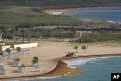 Un tracteur balaie une plage bordée d'algues le long de la côte atlantique à Fregate Bay, Saint-Kitts-et-Nevis, le mercredi 3 août 2022 (AP Photo/Ricardo Mazalan)