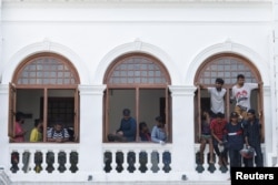 Para demonstran melihat keluar jendela setelah memasuki gedung kantor Perdana Menteri Sri Lanka Ranil Wickremesinghe, di tengah krisis ekonomi negara itu, di Kolombo, Sri Lanka 13 Juli 2022. (REUTERS/Adnan Abidi)