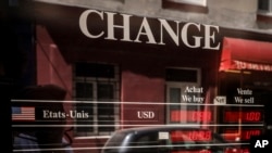 Exchange rates for U.S dollars and the euro currencies are displayed outside a change office, July 13, 2022 in Paris. The euro this month fell to parity with the dollar for the first time in nearly 20 years.