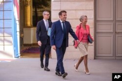 FILE: French President Emmanuel Macron, center, and Prime Minister Elisabeth Borne, right, arrive to attend the first cabinet meeting with new ministers at the Elysee Palace in Paris, July 4, 2022.