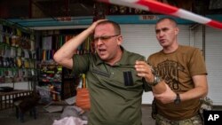 Ukrainian servicemen react after they identify a body of a friend killed by Russian shelling at Barabashovo market in Kharkiv, Ukraine, July 21, 2022.