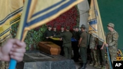 FILE - Soldiers of the Azov regiment pay a last tribute to a serviceman killed in battle against Russian troops, in a city crematorium in Kyiv, Ukraine, July 21, 2022. 