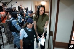 FILE - WNBA star and two-time Olympic gold medalist Brittney Griner is escorted in a court prior to a hearing, in Khimki, just outside Moscow, Russia, Aug. 2, 2022.