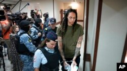 Pemain bola basket Amerika Brittney Griner (kanan) dikawal petugas sebelum hadir dalam pengadilan di pinggiran Moskow, Rusia, hari Selasa (2/8). 