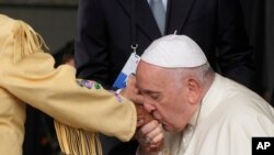 El papa Francisco besa la mano de una mujer indígena canadiense cuando llega al aeropuerto internacional de Edmonton, Canadá, el domingo 24 de julio de 2022.