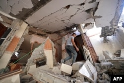 Seorang pria Palestina berjalan di tengah puing-puing rumahnya yang rusak parah, akibat serangan udara Israel di Kota Gaza, 7 Agustus 2022. (MOHAMMED ABED / AFP)