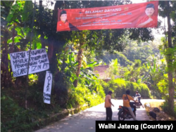 Warga Penawangan memasang poster penolakan tambang di dekat spanduk ucapan selamat datang untuk anggota Komisi V DPR yang datang pada Selasa (26/7).(Foto: Walhi Jateng)