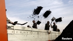 FILE - Laborers unload coal from a truck at a coal dump site in Kabul, Afghanistan.