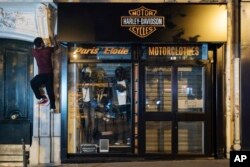 Kevin Ha from the collective "On the Spot" climbs to turn off the lights of a store in Paris, France, July 29, 2022.