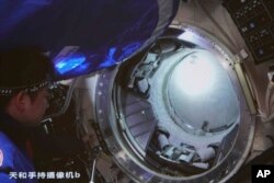 In this photo released by Xinhua News Agency, an image taken off the screen at the Beijing Aerospace Control Center, shows Chinese astronaut Chen Dong opening the hatch door of the Wentian lab module on Monday, July 25, 2022. (Guo Zhongzheng/Xinhua via AP)