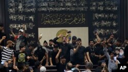 Sejumlah warga Irak merangsek masuk ke dalam gedung parlemen di Baghdad, Irak, pada 31 Juli 2022. Para warga tersebut adalag pendukung ulama Syiah yang terkenal Muqtada al-Sadr. Mereka memprotes pembentukkan pemerintahan oleh rival al-Sadr. (Foto: AP/Anwar Khalil)