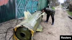 Seorang warga tampak mengamati bagian dari rudal milik pasukan Rusia yang tersisa di desa Kozarovychi, di dekat Kyiv, Ukraina, pada 22 April 2022. (Foto: Reuters/Viacheslav Ratynskyi)