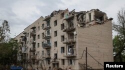 Local residents look at their residential building damaged by a Russian military strike, amid Russia's invasion on Ukraine, in the town of Chasiv Yar, in Donetsk region, Ukraine, on July 11, 2022. 