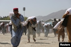 FILE - Afghan people carry sacks of rice, given out as part of humanitarian aid sent by China to Afghanistan, at a distribution center in Kabul, Afghanistan, April 7, 2022.