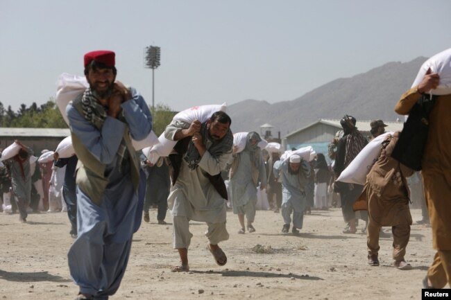 DOSJE - Njerëzit afganë mbajnë thasë me oriz, të dhëna si pjesë e ndihmës humanitare të dërguar nga Kina në Afganistan, në një qendër shpërndarjeje në Kabul, Afganistan, 7 Prill 2022.