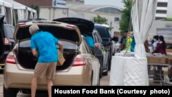 In this undated photo, vehicles line up at a Houston, Texas, food distribution site sponsored by the Houston Food Bank.