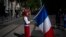 FILE - A woman dressed up as Marianne, a symbol of the French republic since the 1789 revolution, holds a French flag during a May Day demonstration in Marseille, France, May 1, 2022. 