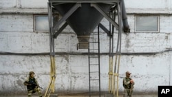 Soldados rusos vigilan un área mientras periodistas extranjeros visitan un elevador de granos en Melitopol, en el sur de Ucrania, el jueves 14 de julio de 2022. (Foto AP)